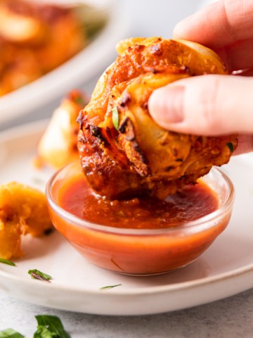 pizza roll being dipped in marinara sauce
