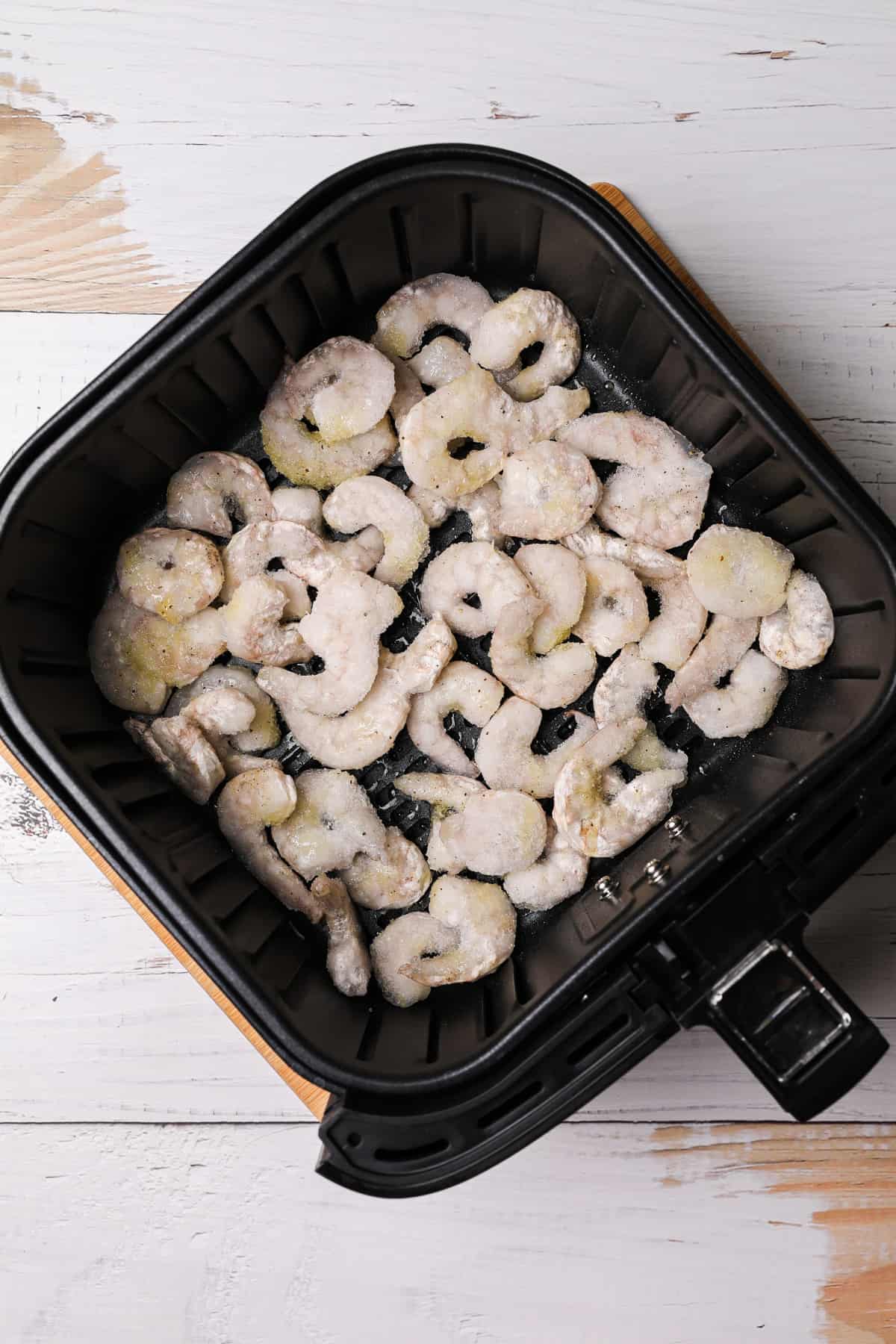 frozen uncooked shrimp in an air fryer basket