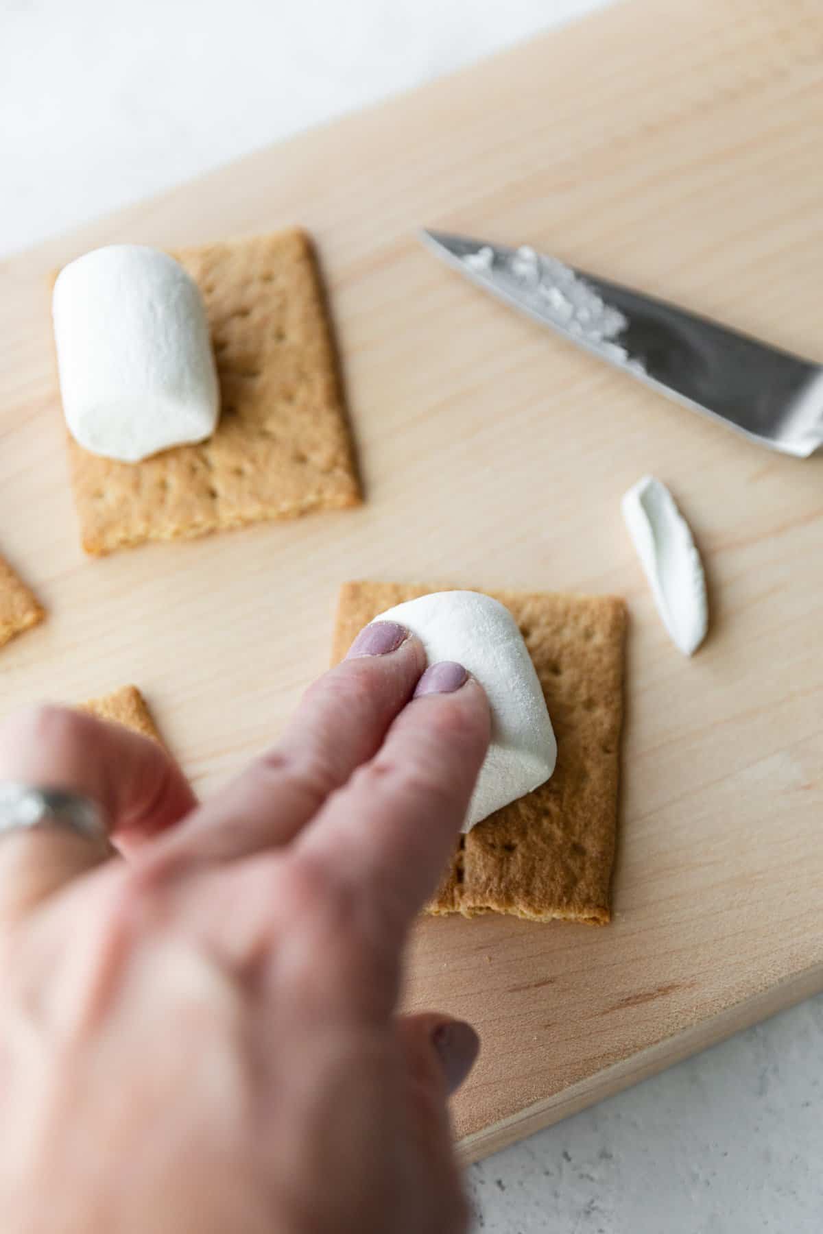 pressing a marshmallow onto a graham crakcer