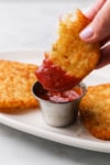dipping a piece of a hash brown patty in ketchup