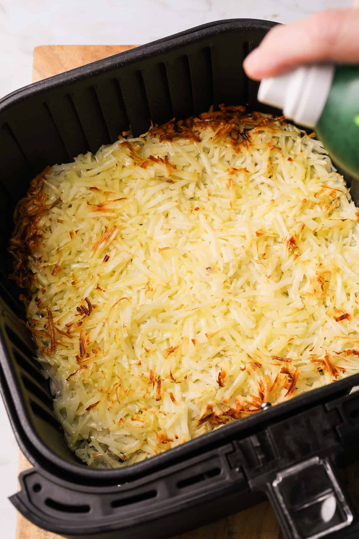 cooked hash browns in an air fryer basket