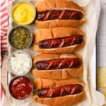 hot dogs in buns with condiments on the side