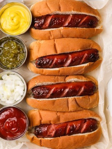 hot dogs in buns with condiments on the side
