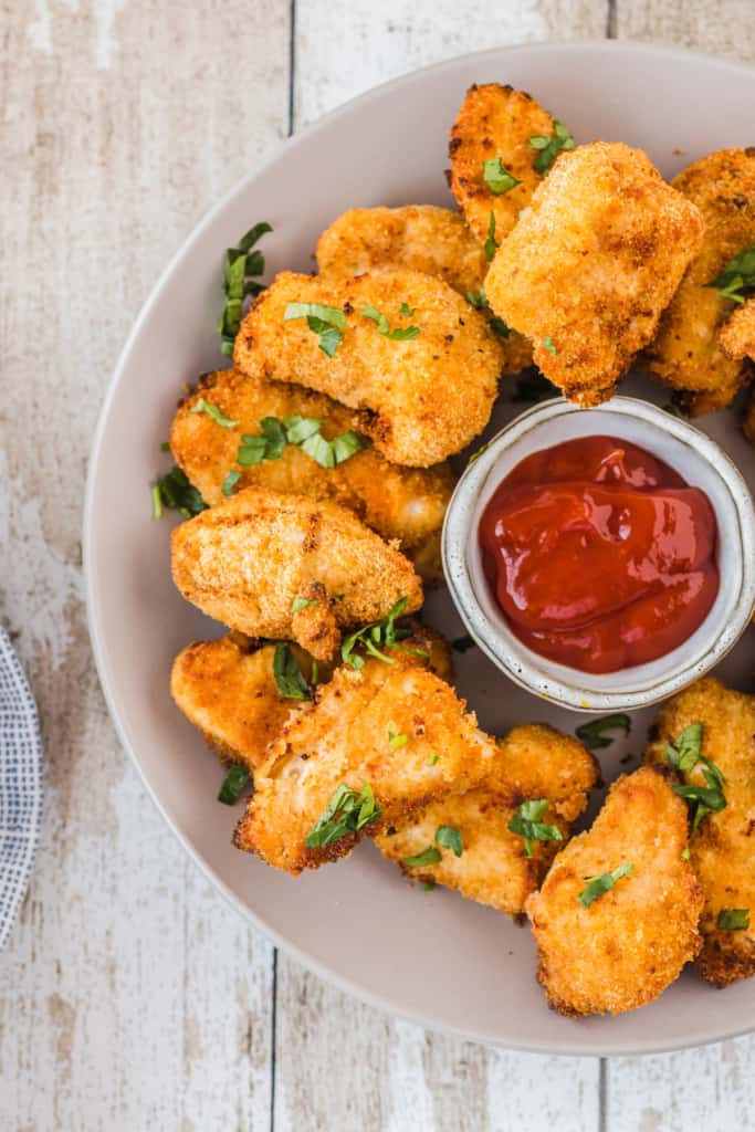 chicken nuggets on a plate with ketchup
