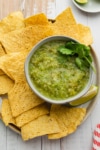 a bowl of green salsa with chips
