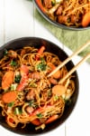 a bowl of lo mein noodles with vegetables and chopsticks