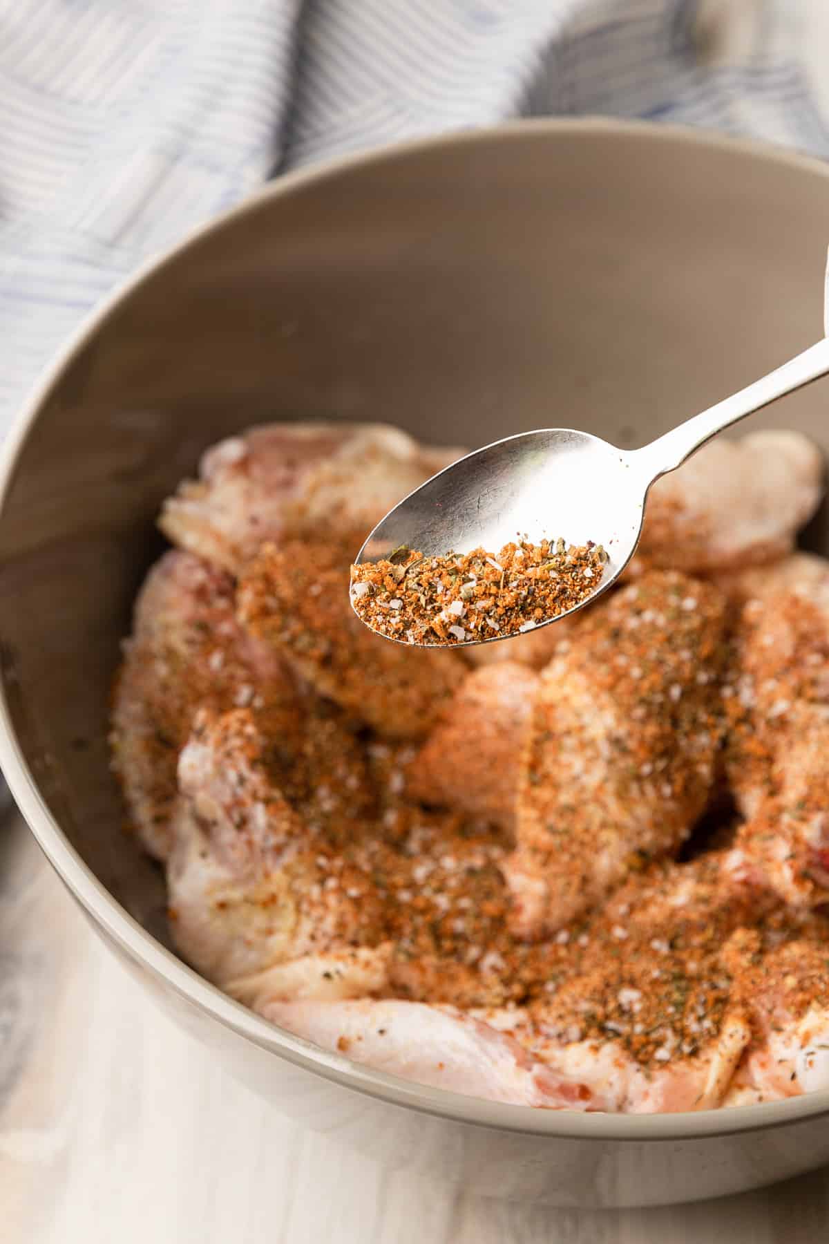 dry rub mixture added to raw wings in a bowl.