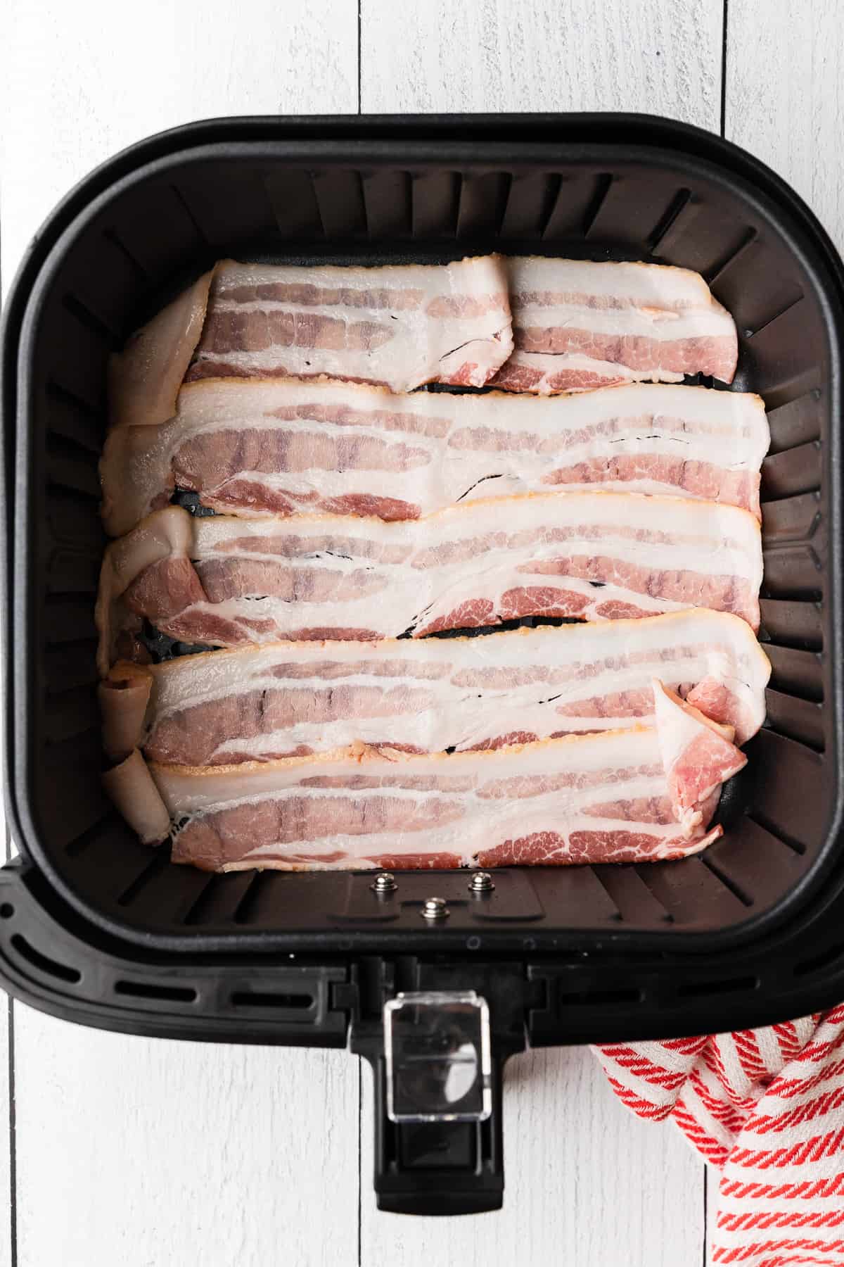 bacon slices in the air fryer basket before cooking