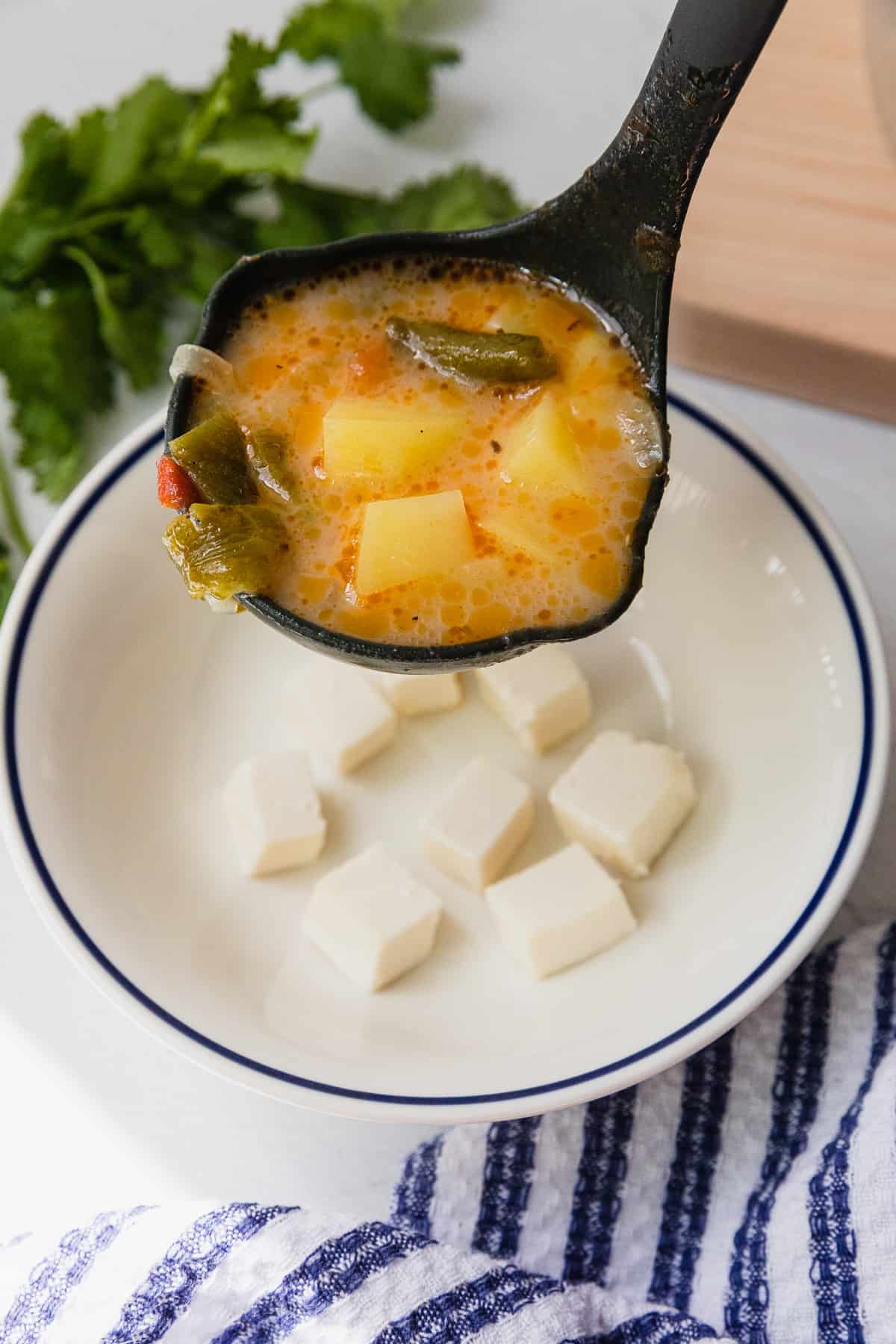 cheese cubes in a soup bowl with soup being poured over