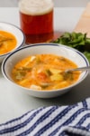 a bowl caldo de queso soup with a glass of beer