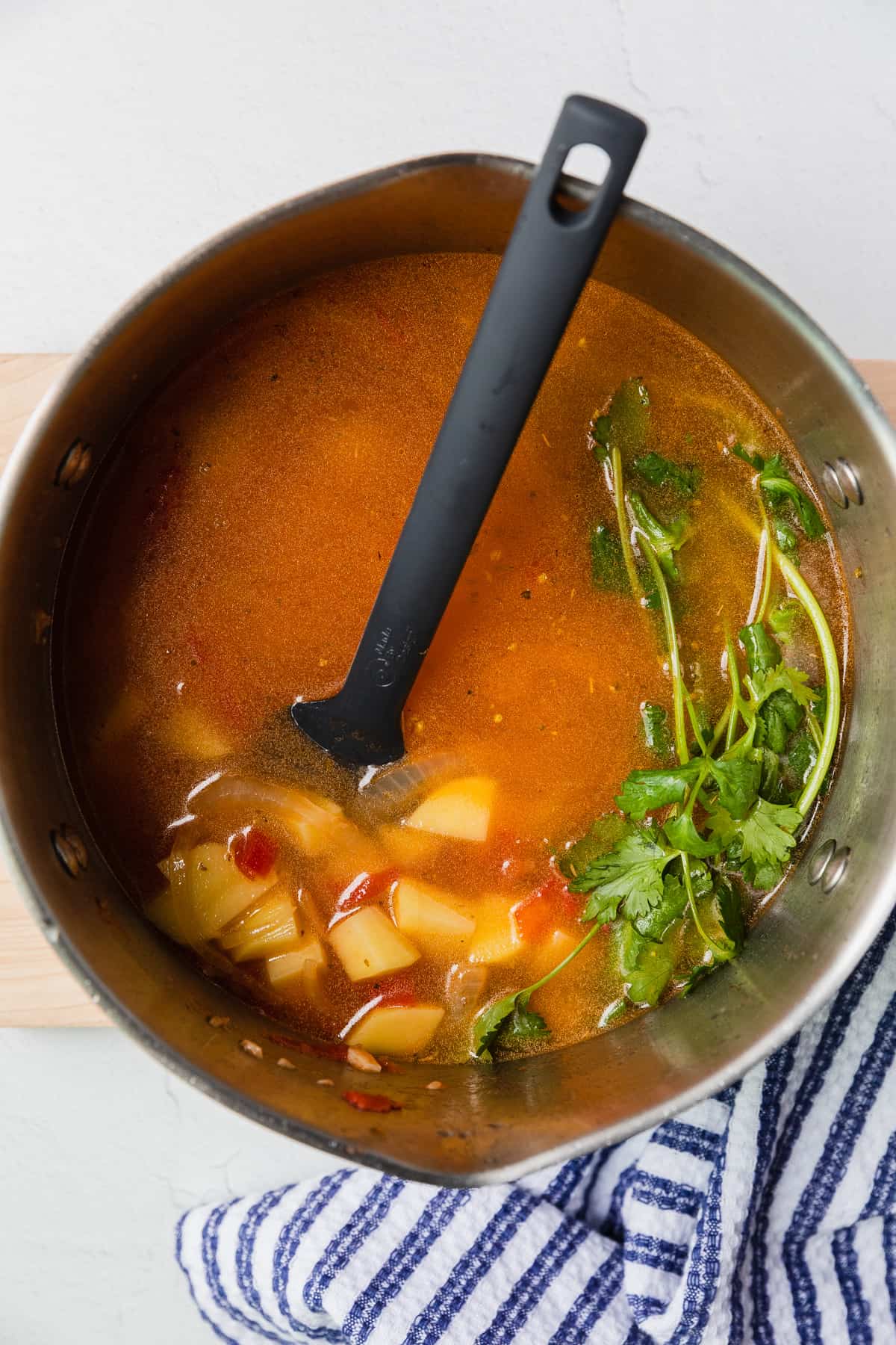 adding broth and cilantro to soup pot