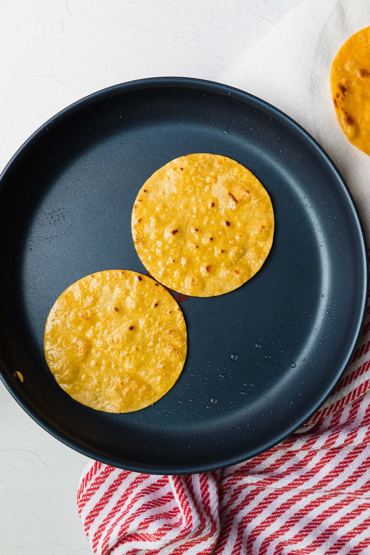 frying corn tortillas in a skillet