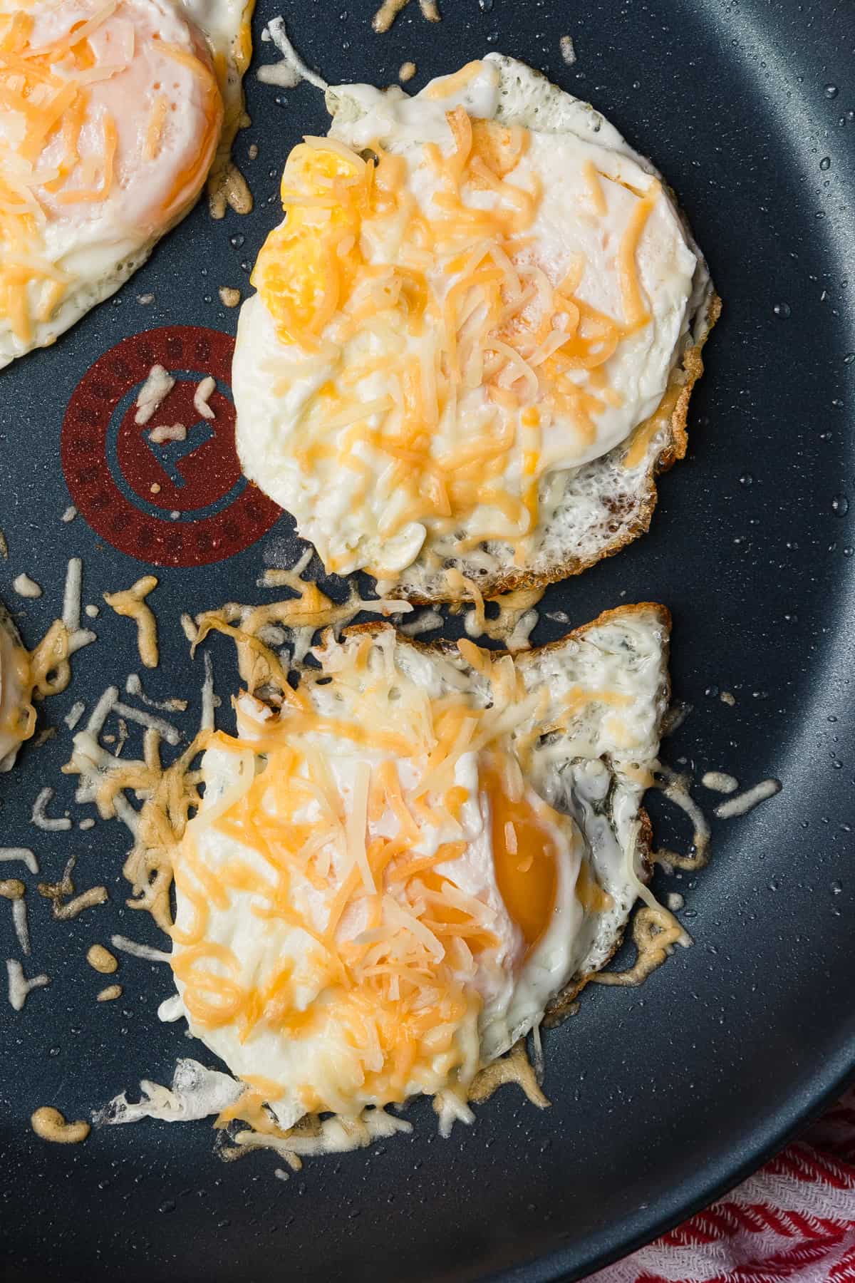 cooked eggs in skillet topped with cheese