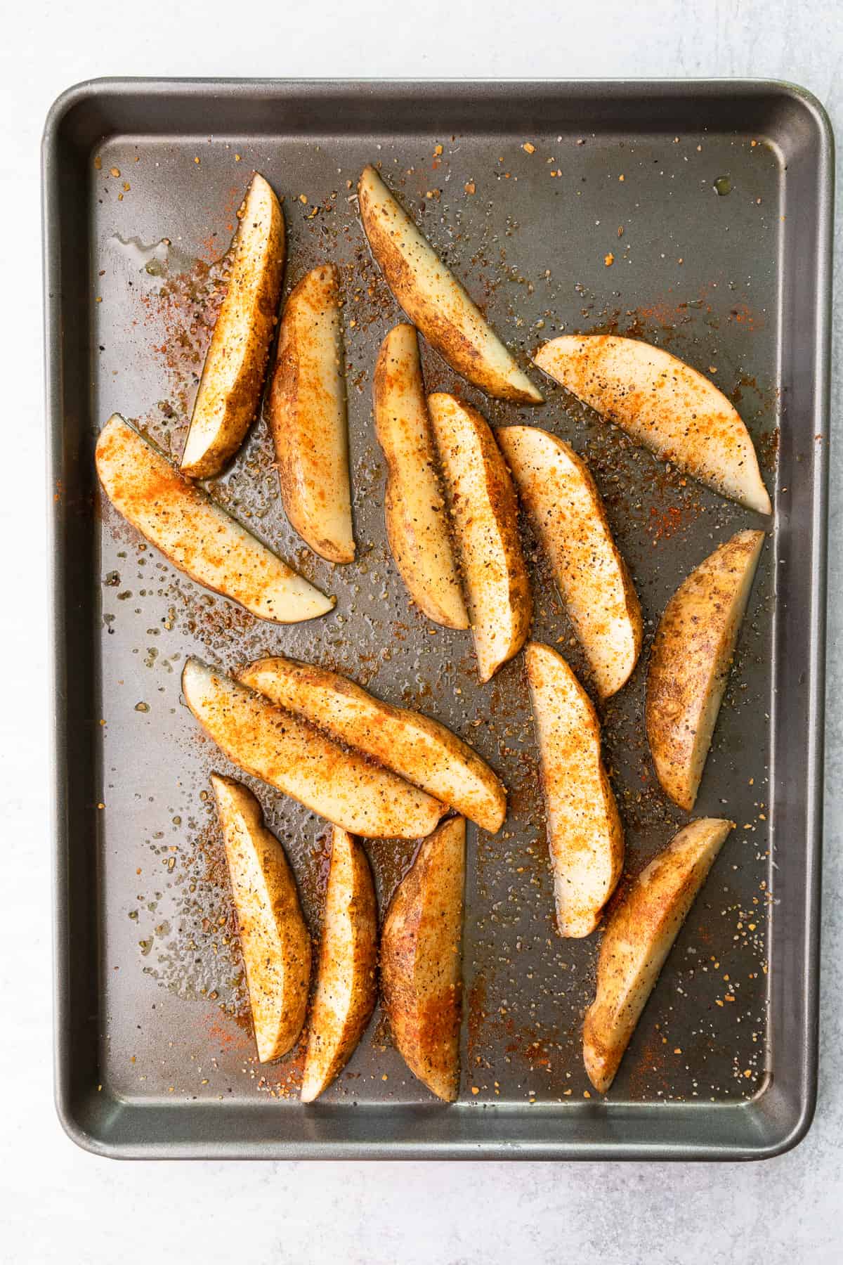 potato wedges on a baking sheet with seasonings