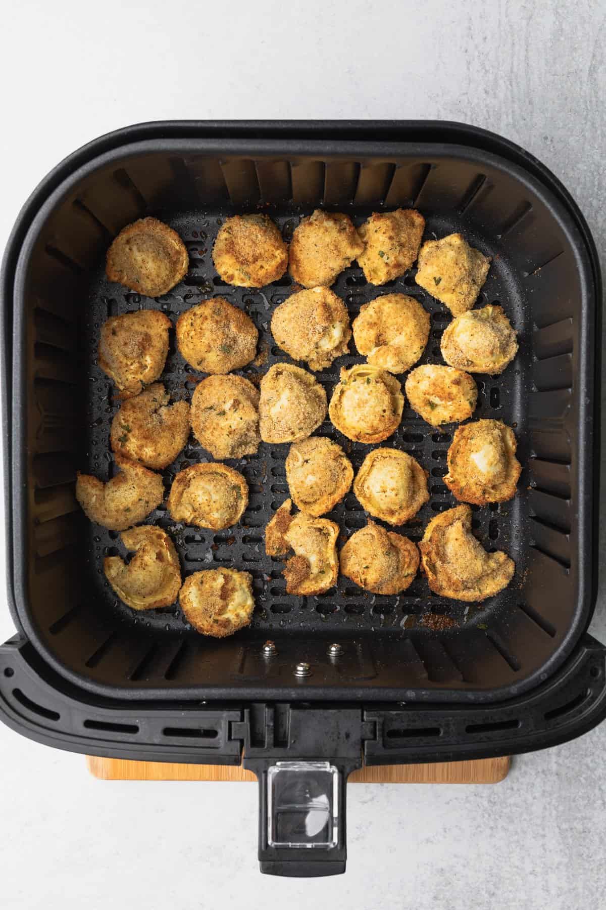 air fryer basket with partially cooked tortellini