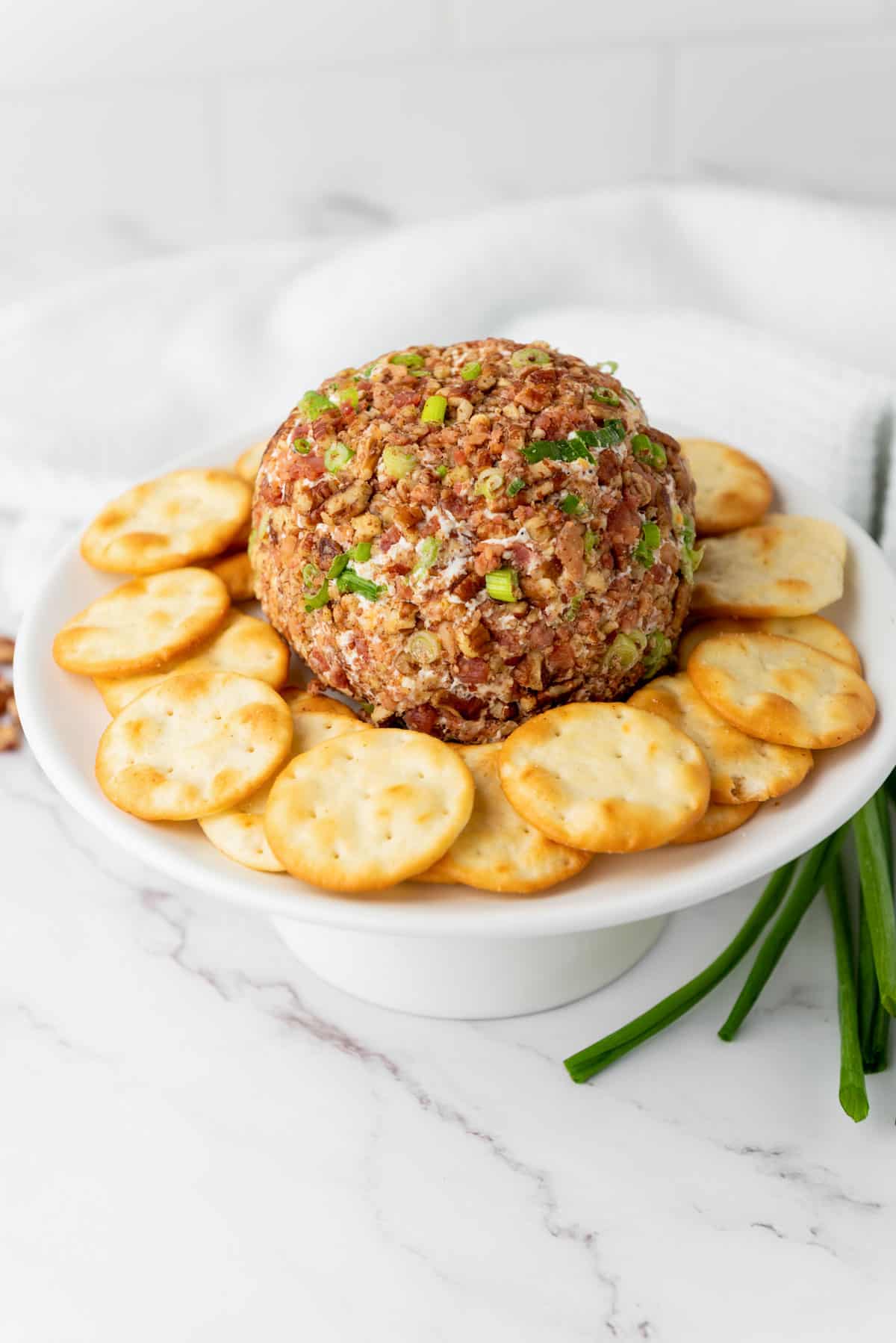 cheese ball surrounded by crackers on a cake stand