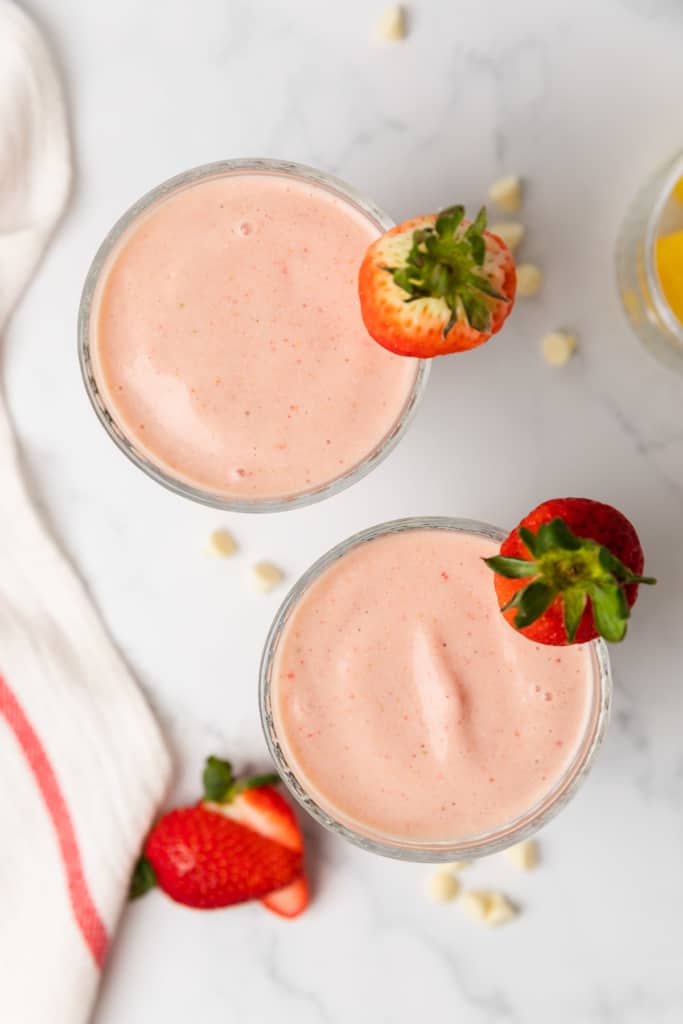 two pink smoothies in glasses with strawberry garnish