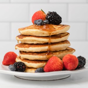 stack of evaporated milk pancakes with fresh fruit and syrup