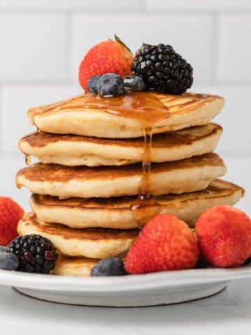 stack of evaporated milk pancakes with fresh fruit and syrup