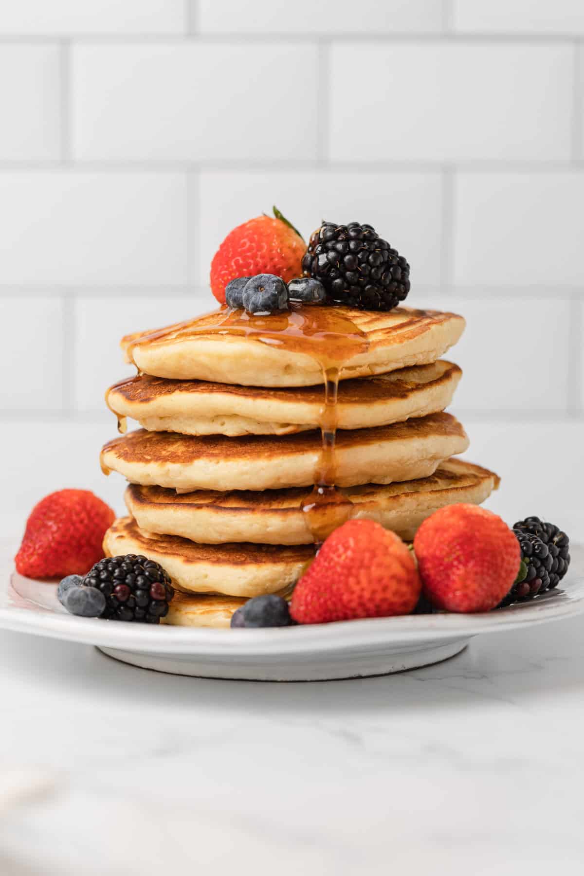 a stack of pancakes with fresh fruit and syrup