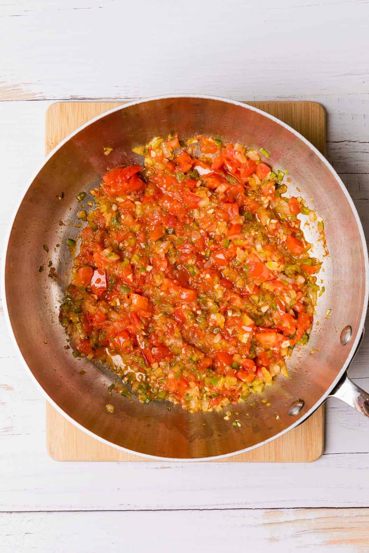 adding fresh tomatoes to make the sauce