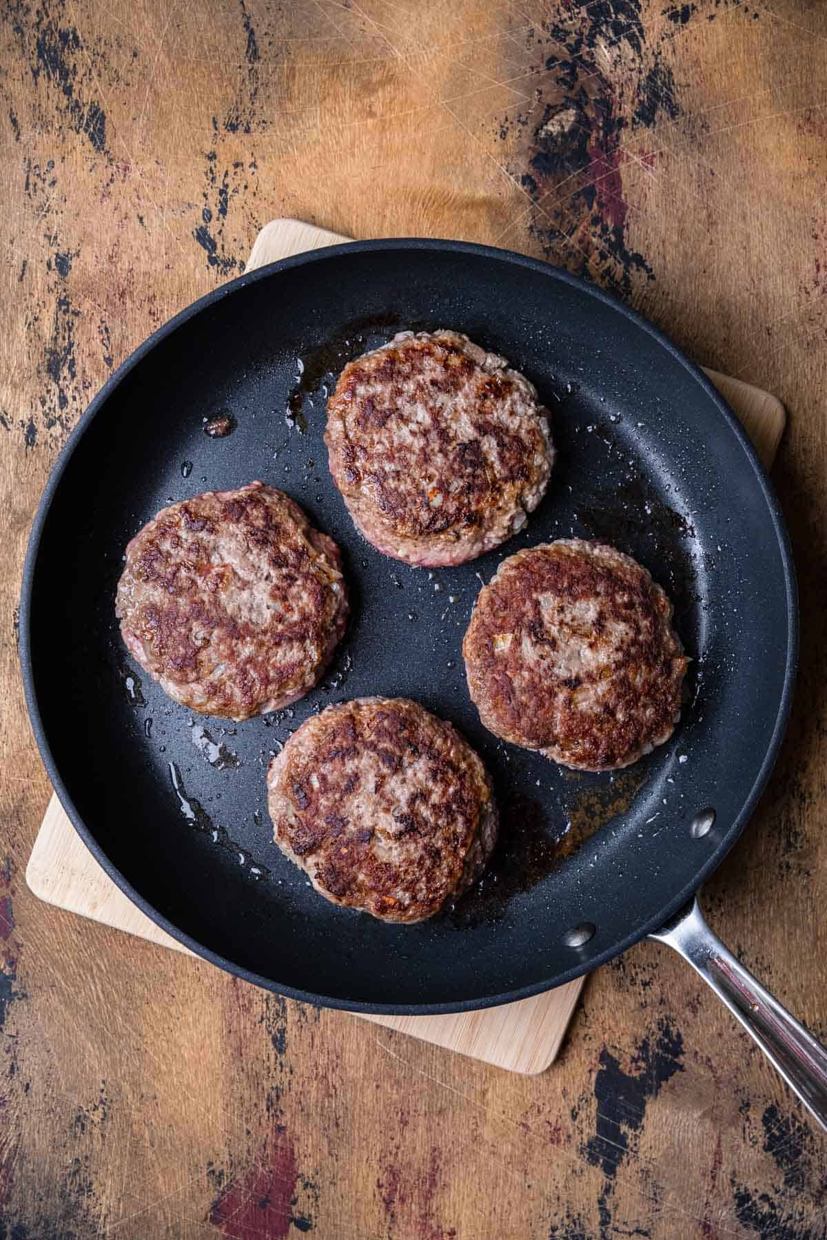 cooking hamburger patties in a skillet