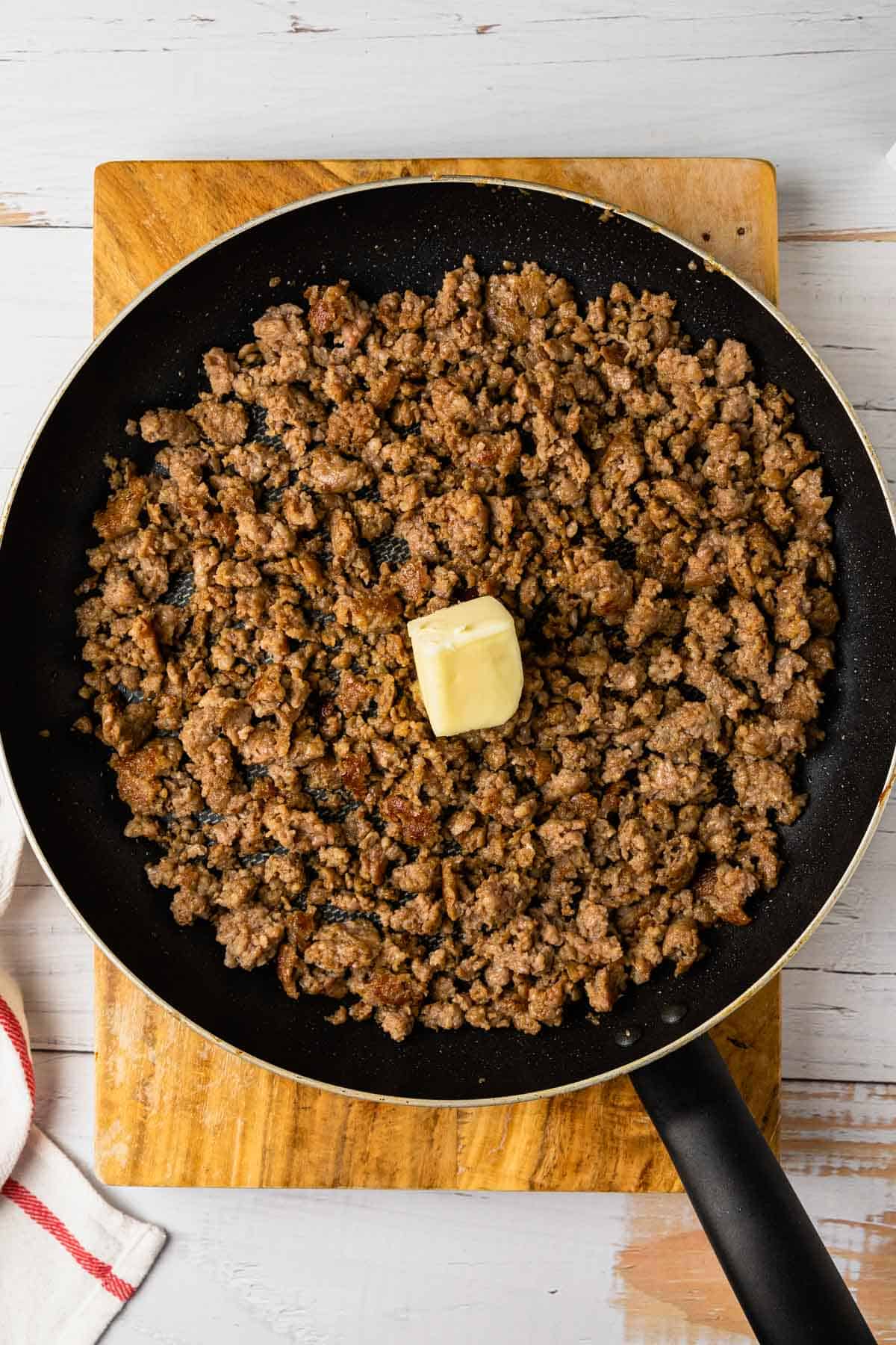cooked sausage in a skillet with a pat of butter