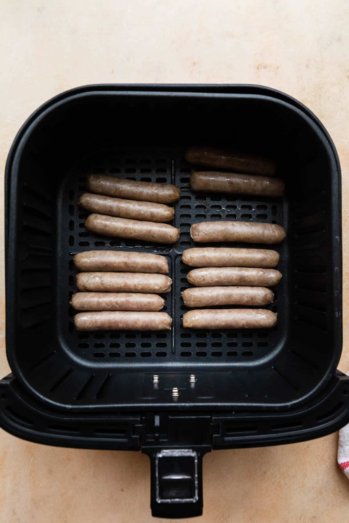 sausage links in air fryer basket cooked at the halfway point