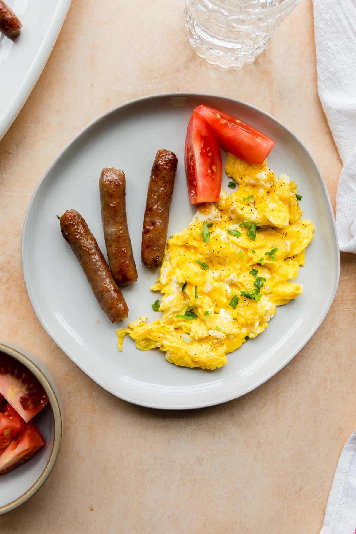 a plate of air fryer sausage links with eggs and tomatoes
