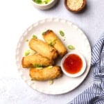 tai pei egg rolls on a plate with sweet and sour dipping sauce