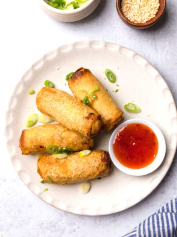 tai pei egg rolls on a plate with sweet and sour dipping sauce