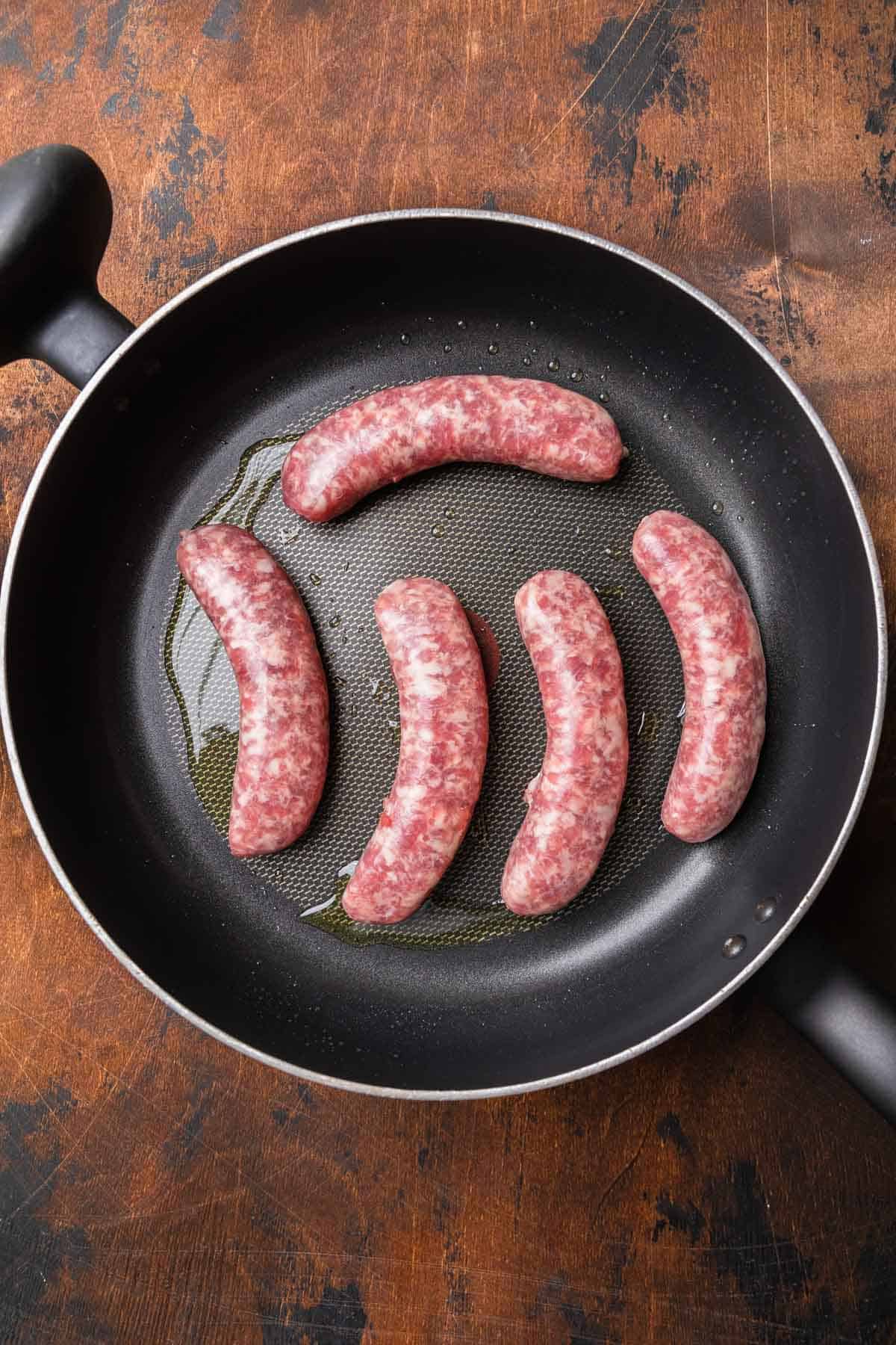 frying bratwurst in a large skillet