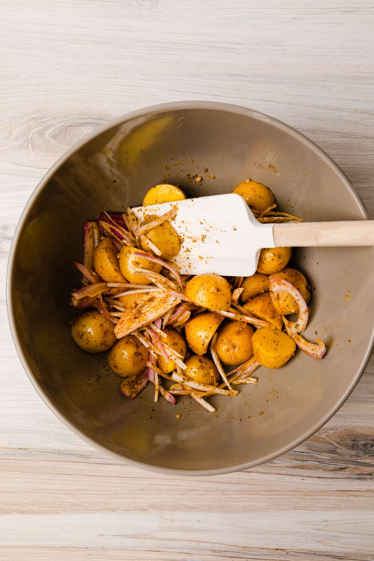 Making the recipe by mixing seasoning with potatoes.