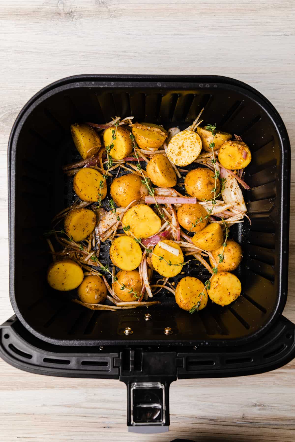 Putting the seasoned potatoes in the air fryer. basket.