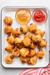 The completed pig in a blanket recipe on a white platter.