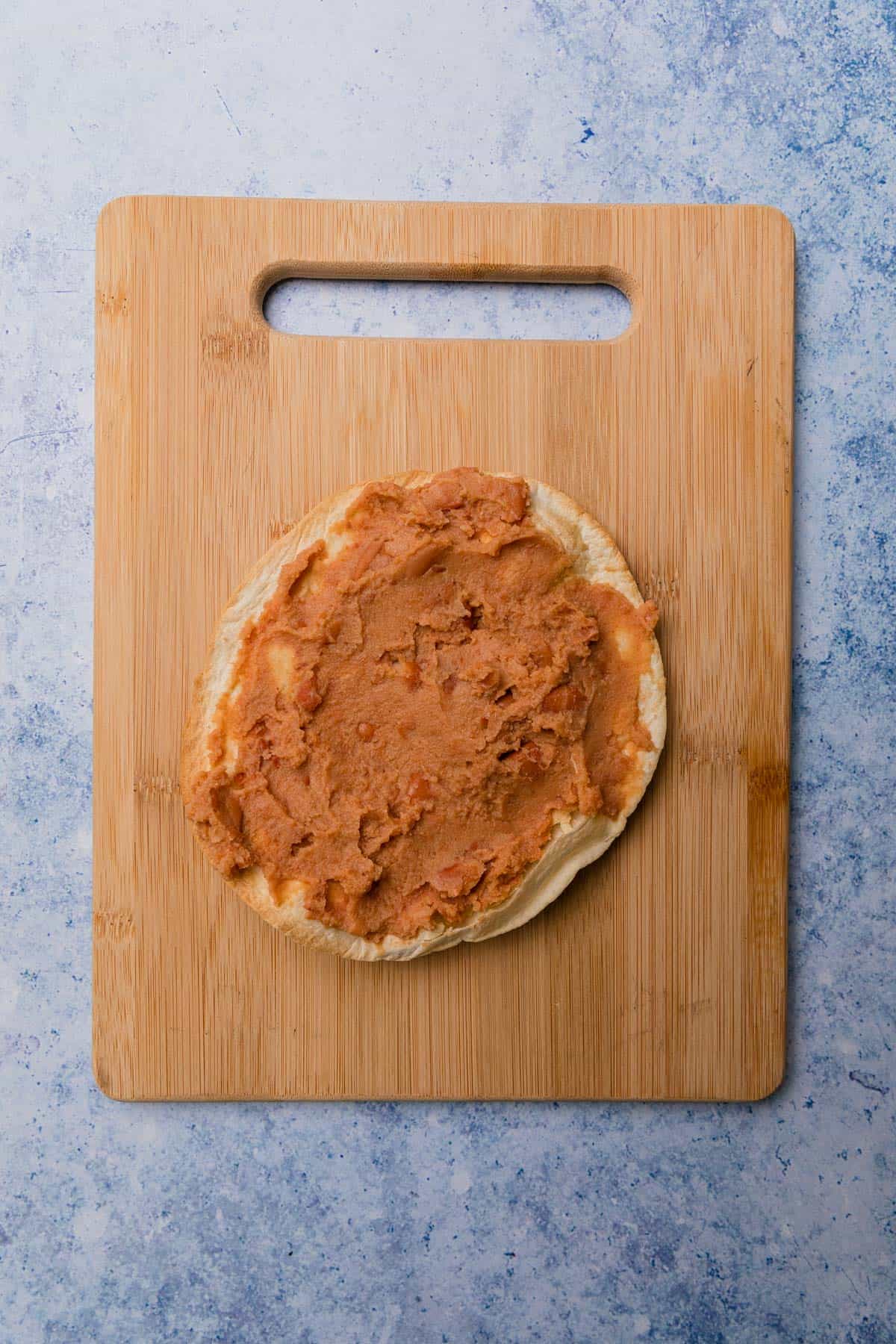 adding beans to the tostada