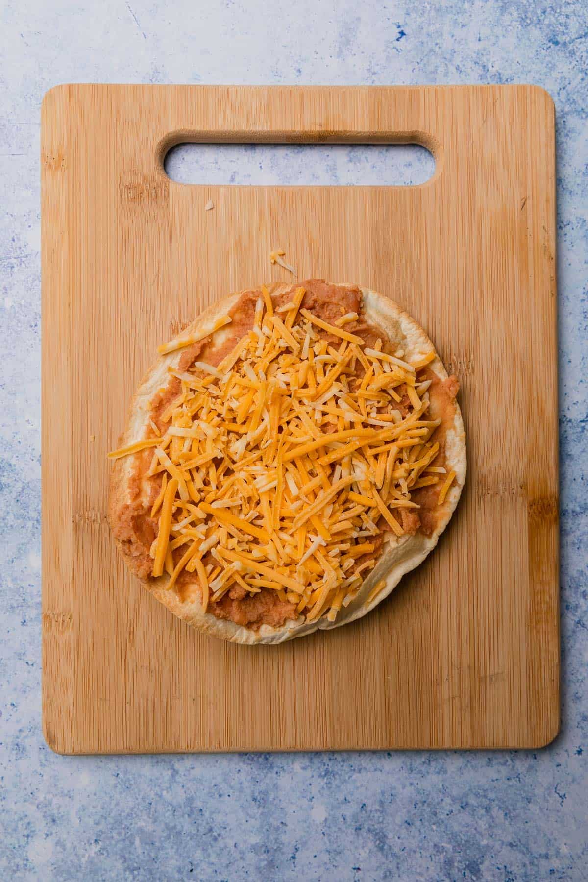 adding cheese to the top of the beans layer