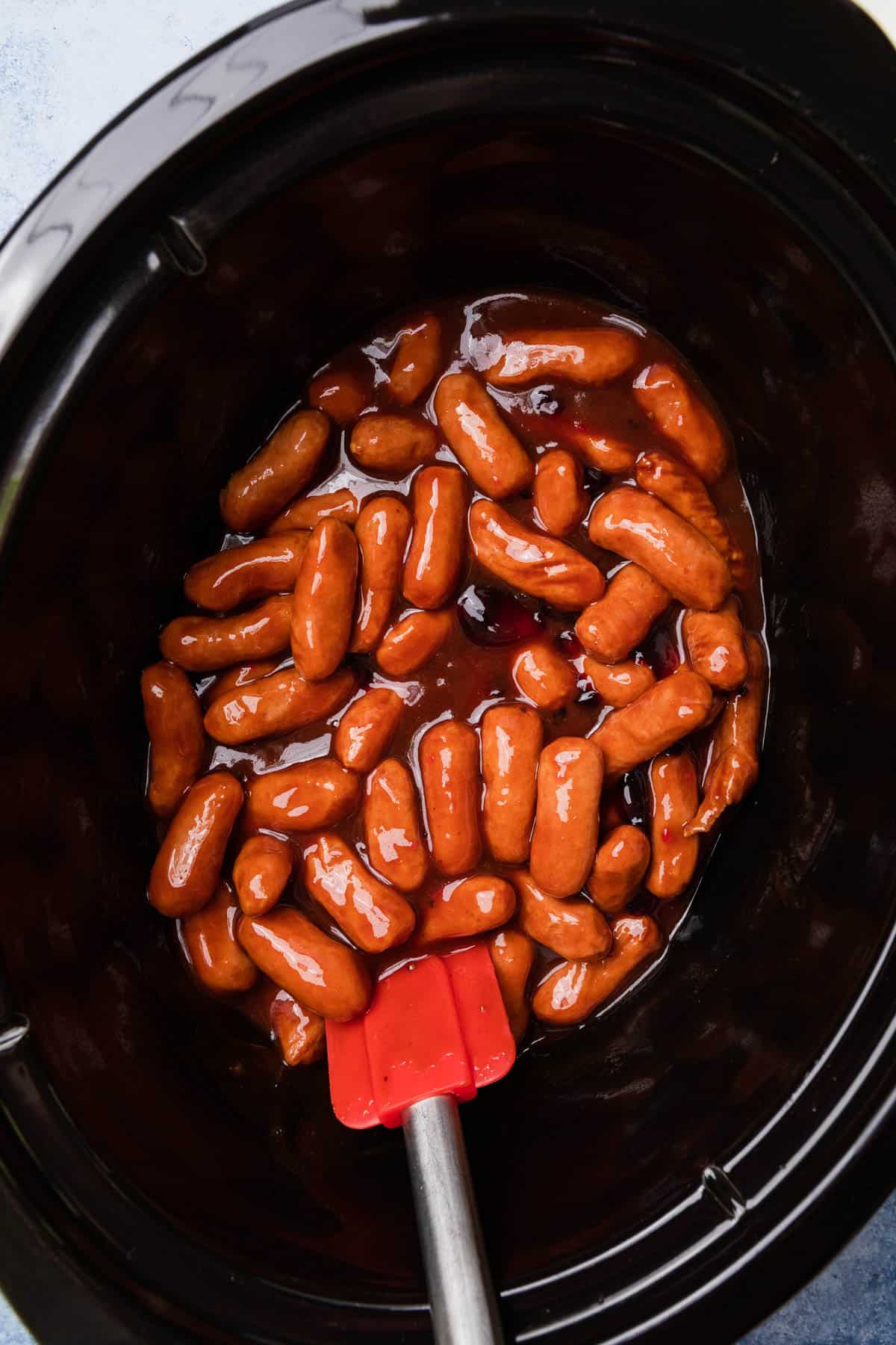 stirring the bbq sauce with the little smokies in a crockpot