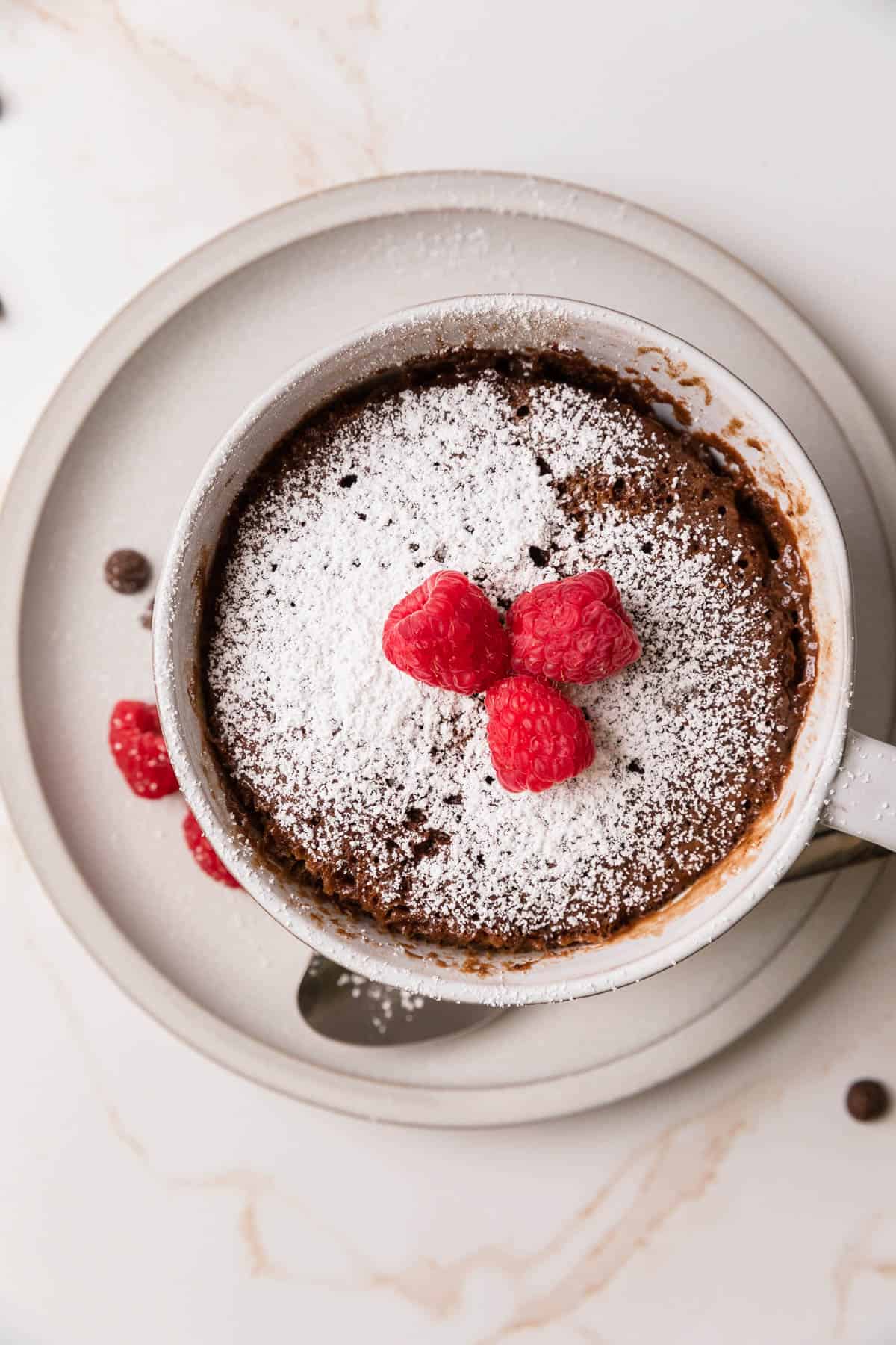 adding fresh raspberries and powdered sugar to the mug cake