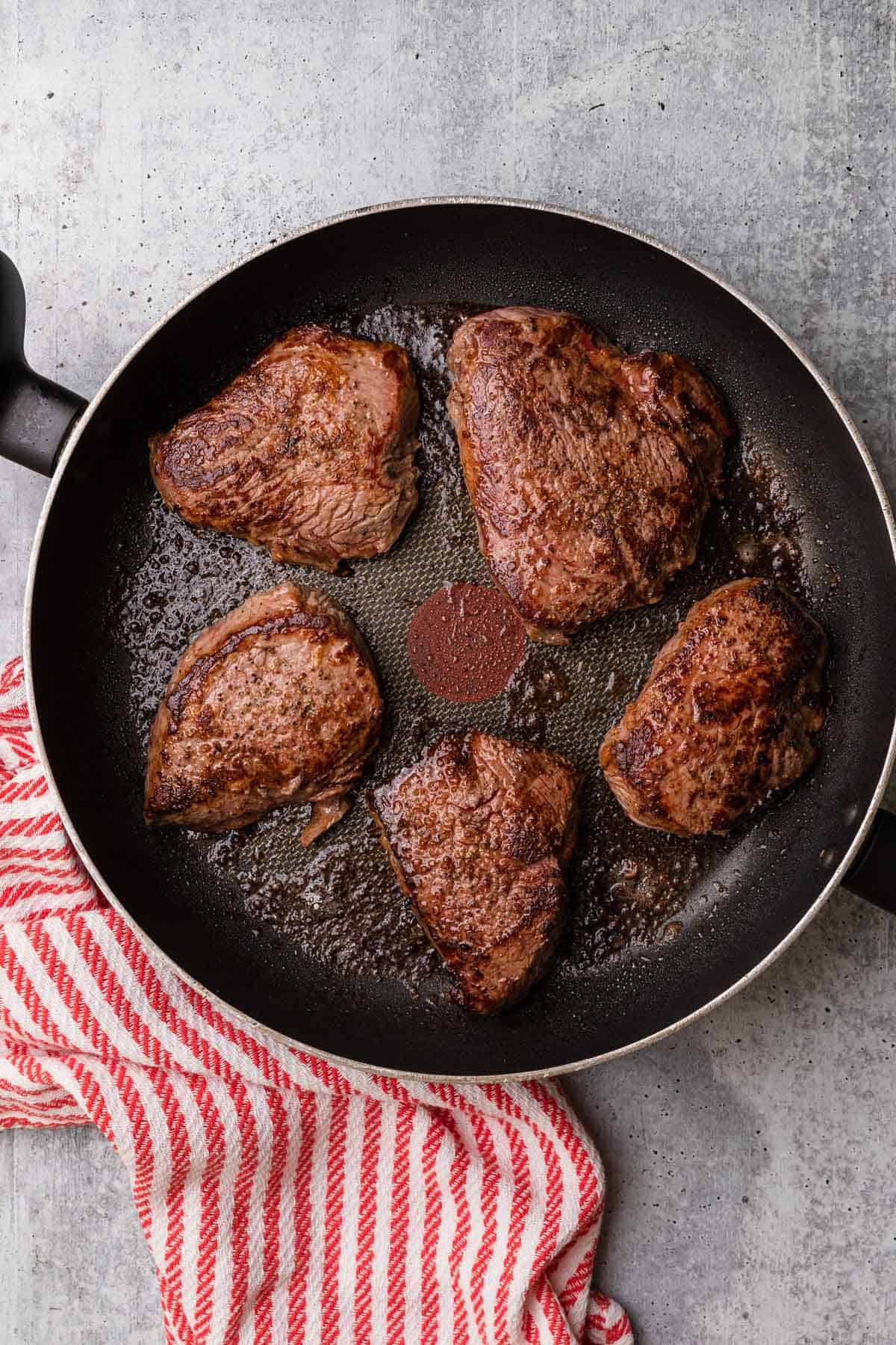 skillet with cooking steaks