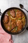 simmering the steaks and peppers in the gravy in the skillet to complete the cooking process