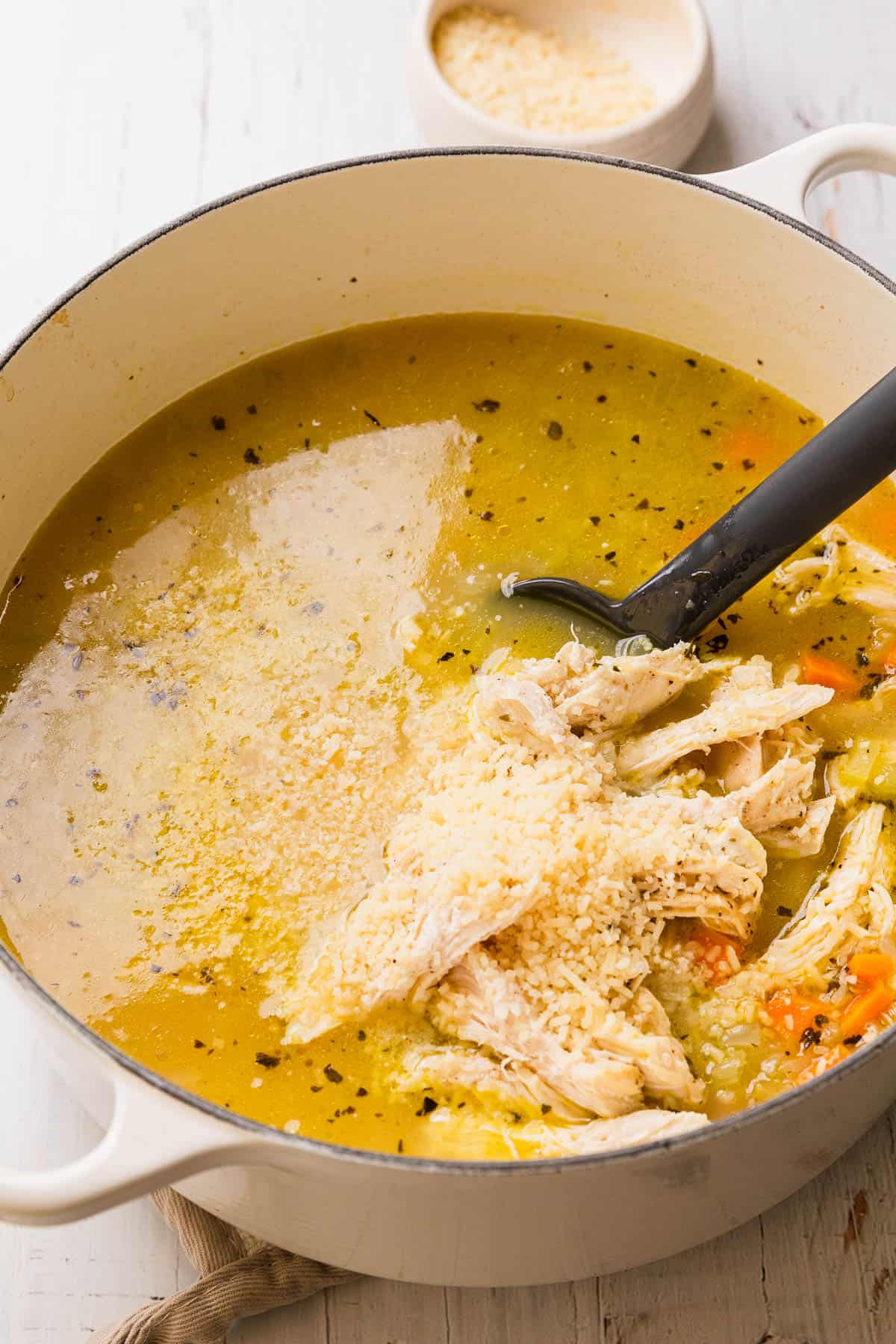 Adding parmesan to chicken soup.