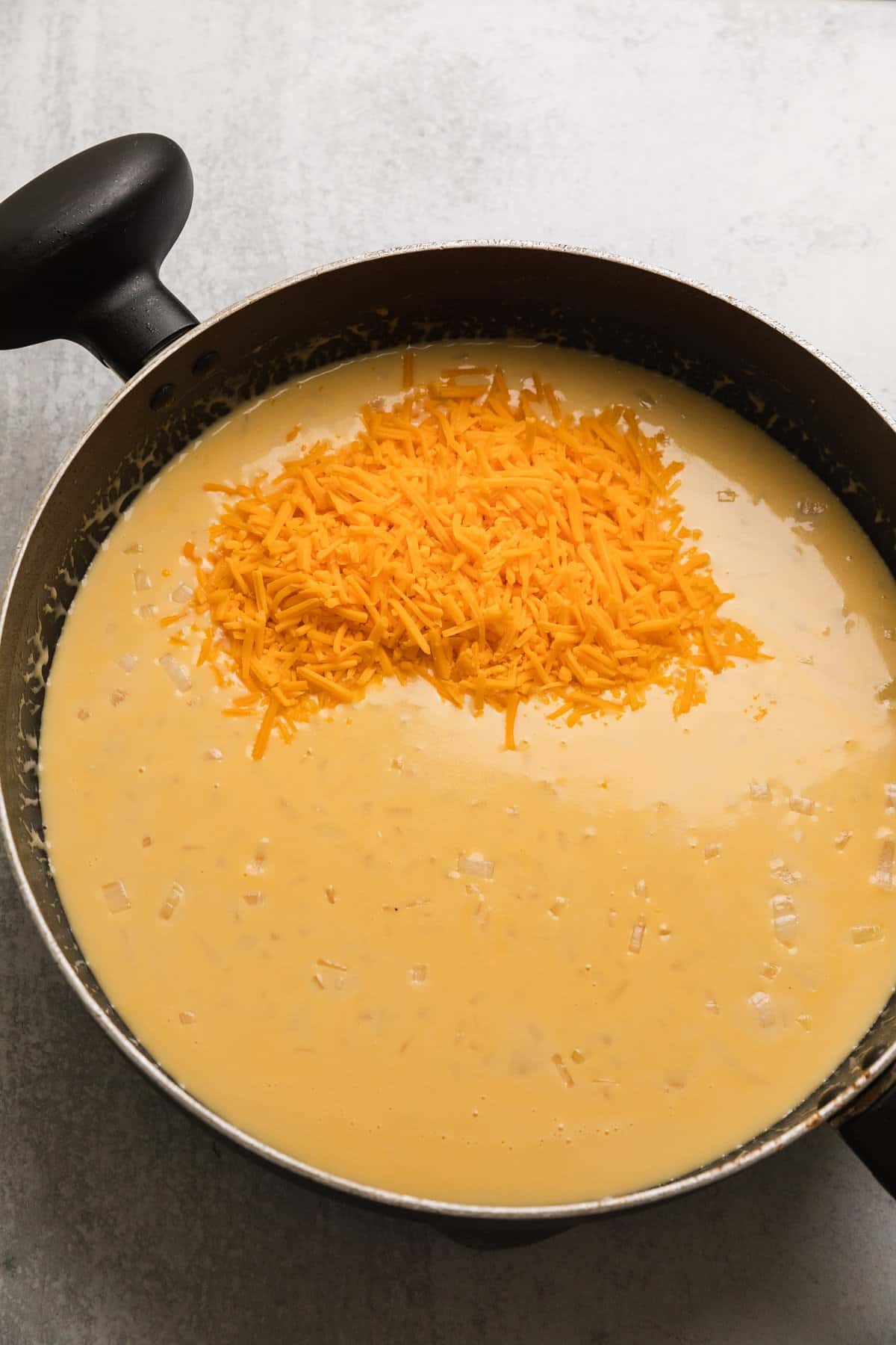 adding shredded cheese to make the recipe