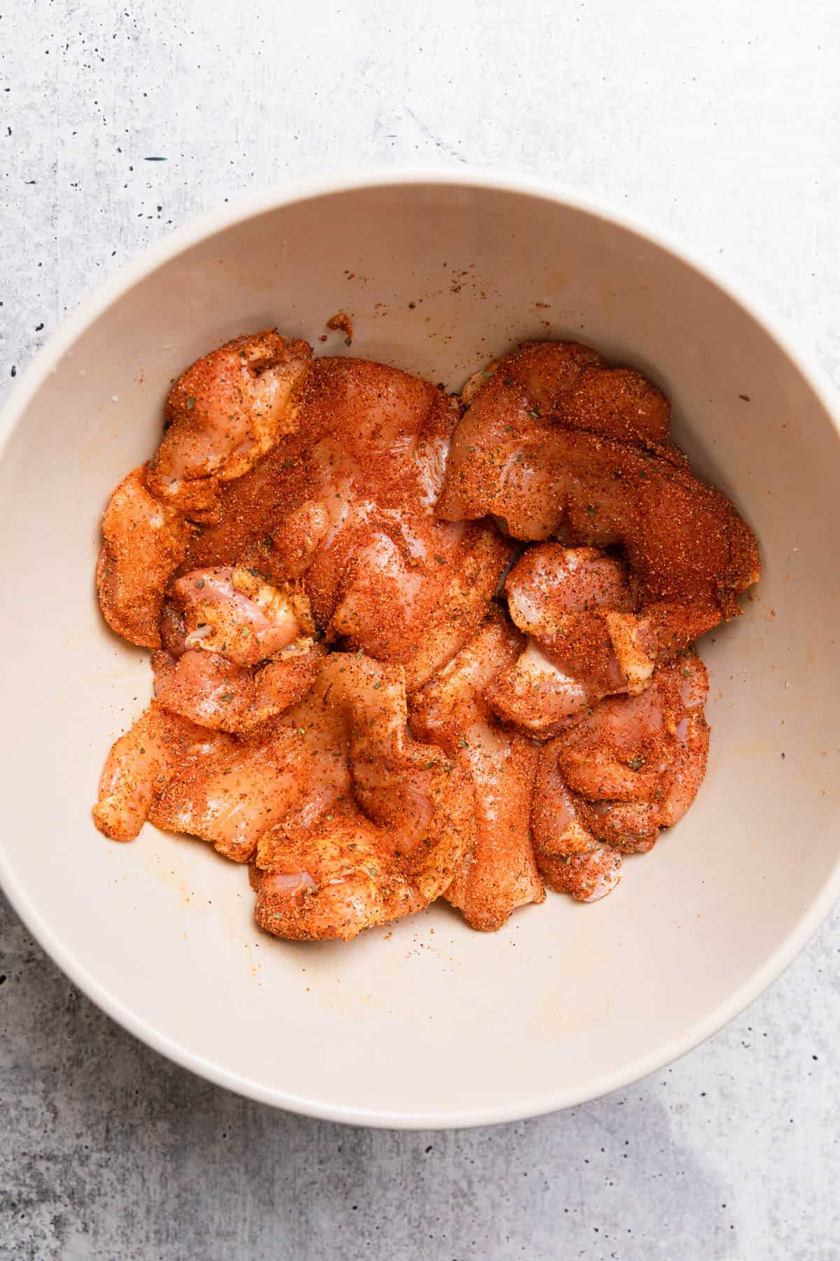 Covering chicken thighs with spice rub.