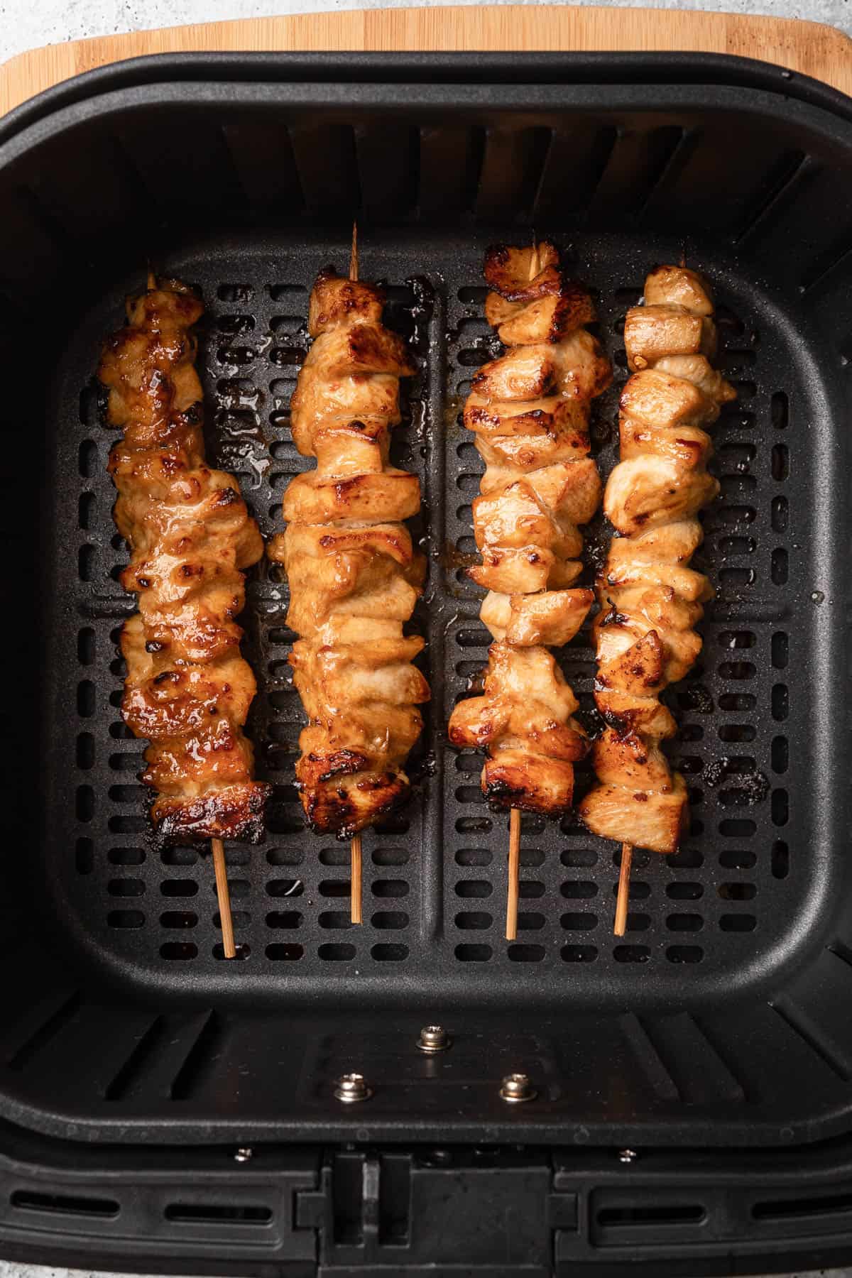 Skewered chicken in air fryer basket after cooked.