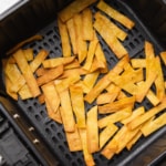 Cooked tortilla strips in air fryer basket.