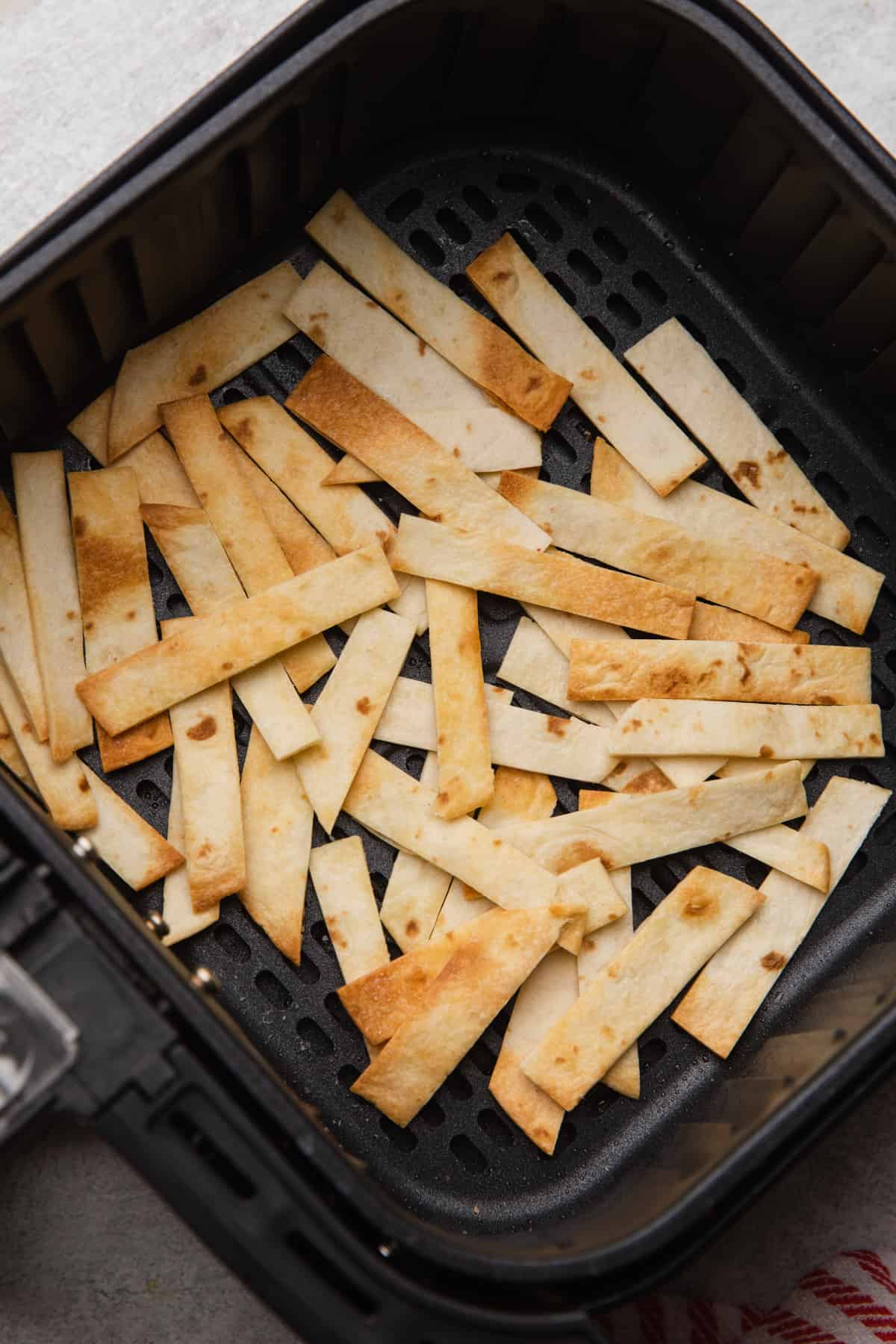 Flour tortilla strips air fried to a golden brown.