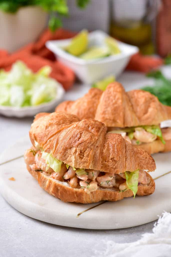 Two shrimp salad sandwiches on a plate.