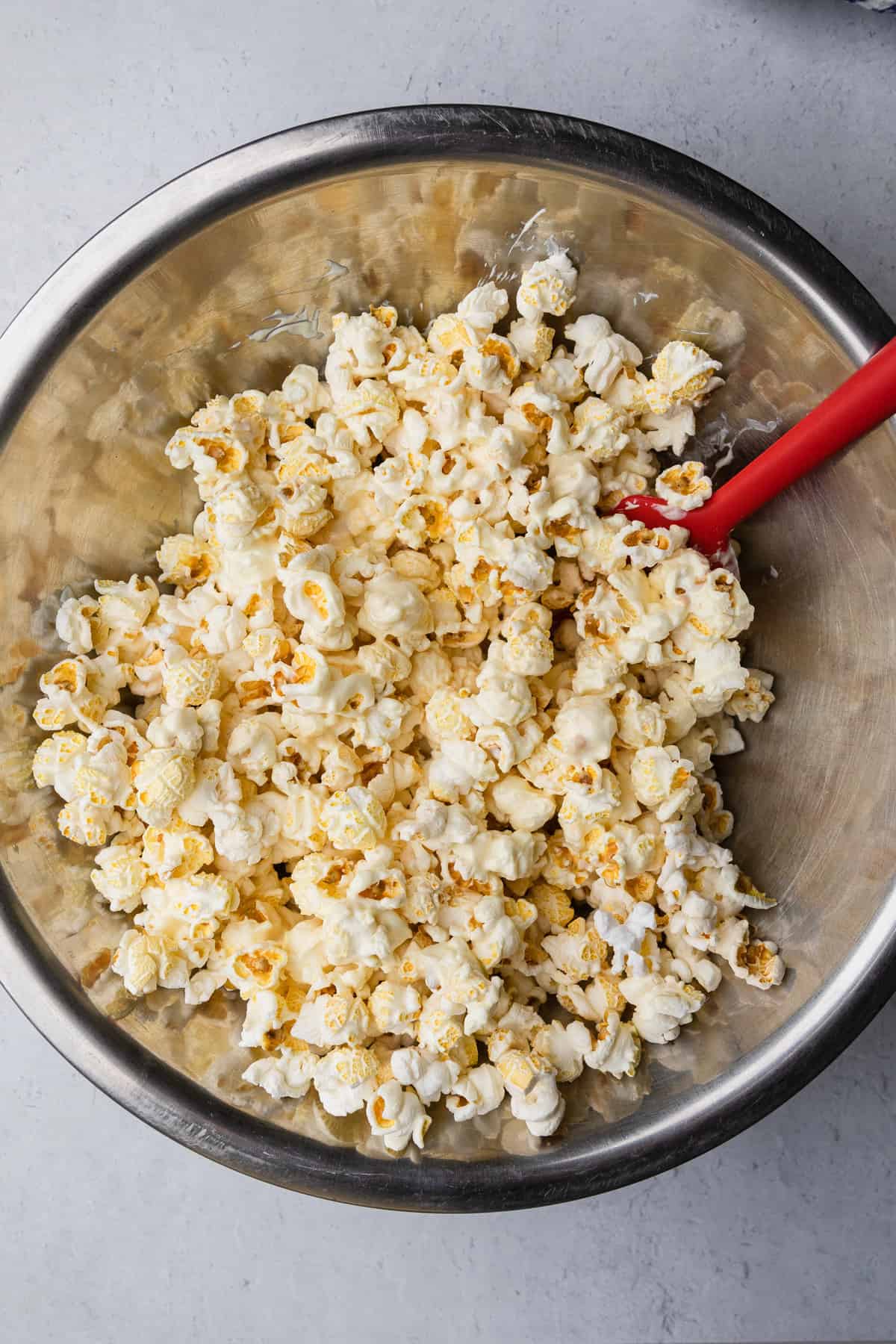 Mixing melted white chocolate with popcorn.