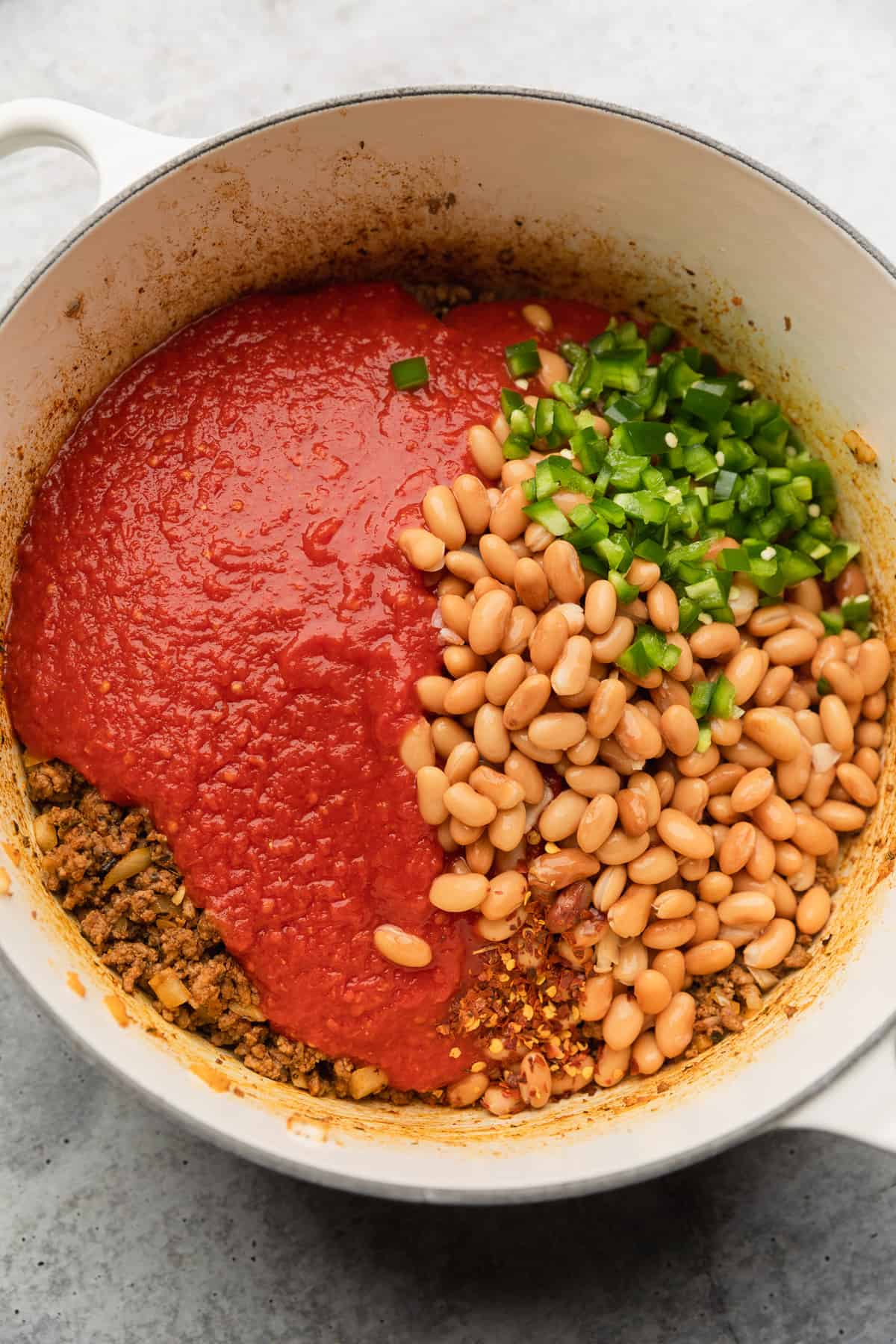 Adding beans and jalapenos to the pot.